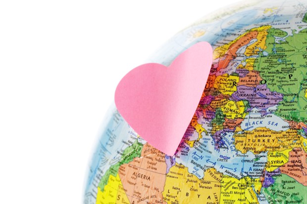 Earth globe and paper heart on white