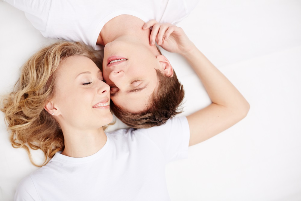 Two young dates with closed eyes lying in bed